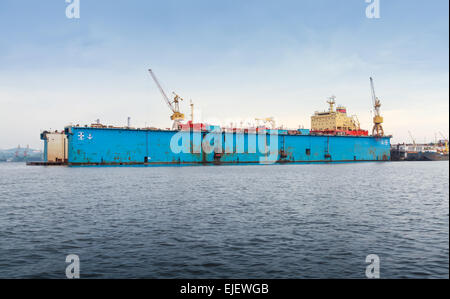 Floating blu dock a secco con la petroliera rossa sotto la riparazione all'interno Foto Stock