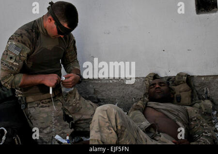 Stati Uniti Army Spc. Trento McIlwraith, di Edmond, Okla., un combattimento medic per Bravo Company, 1-179th fanteria, 45th della brigata di fanteria combattere la squadra, amministra I.V. a Tech Sgt. Gevoyd piccolo, di Columbus, Ohio, un esplosivo ordinanza smaltimento supporto tecnico forza taskforce Maverick in cuor di Leone di funzionamento sul Sett. 12. Foto Stock