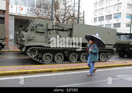 Atene, Grecia. Xxv Marzo 2015. Un uomo cammina oltre la US M270 Lancio multiplo Sistema razzo semovente, più rocket launcher precedendo la parata militare di Atene. I partecipanti della parata militare che si terrà ad Atene, per celebrare il 194th indipendenza greca il giorno ottenere pronto. Il giorno celebra l'inizio della guerra greca di indipendenza nel 1821, che portano all'indipendenza della Grecia dall'Impero Ottomano. Credito: Michael Debets/Alamy Live News Foto Stock