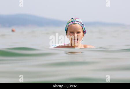 Bambino nuota nel mare su anello gonfiabile in una limpida giornata di sole. Profondità di campo. Focus sul modello. Foto Stock