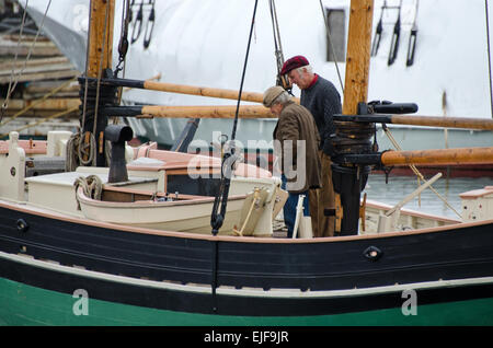 Due uomini in un vecchio stile caps esaminare una barca di legno nel porto di Camden, Maine (USA). Foto Stock