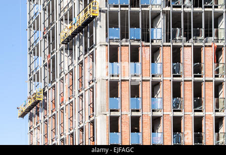 Un alto edificio di uffici in costruzione con i lavoratori che operano sulla build Foto Stock