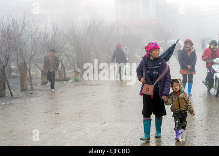 Hmong donna cammina con un bambino in un mercato di Sapa, Vietnam Foto Stock