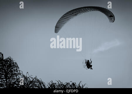 Un powered pilota di parapendio in volo con un blu cielo pulito in background Foto Stock