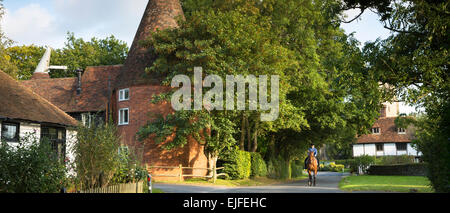 Cavallo e cavaliere nel pittoresco villaggio affascinante di Smarden con tradizionale Kentish oast house in alta Weald nel Kent, England, Regno Unito Foto Stock