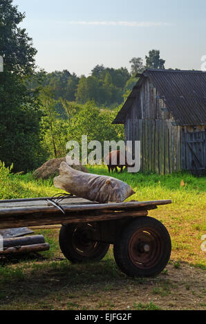 Paesaggio rurale. Villaggio granaio, mucche e cavalli carrello. Foto Stock