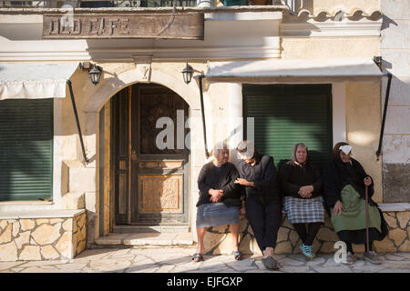 Tipici Corfi oti anziane donne che indossano tradizionali vestiti di nero seduta rilassante nella piazza del villaggio di Krini, Corfù, , Grecia Foto Stock