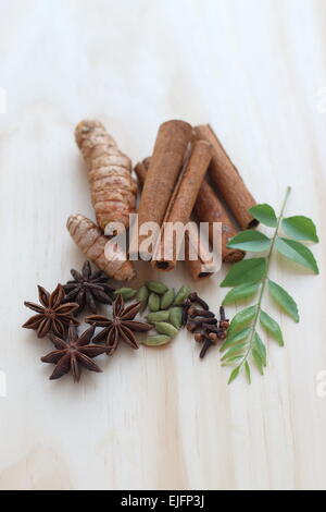 Un assortimento di spezie secche compresi murraya koenigii su una tavola di legno Foto Stock