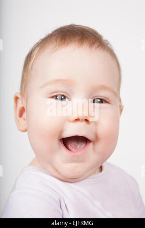 Ritratto di otto mesi di età adorabile bionda simpatico baby in velluto rosa sorridente onesie faccia felice isolato su bianco Foto Stock
