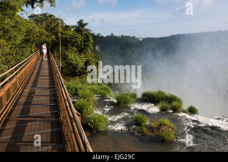 Argentina, Iguazu Falls, turisti sul marciapiede al di sopra dell'acqua che scorre sopra le cascate Foto Stock