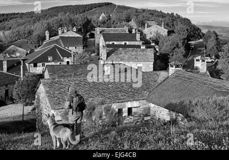 Spagna Galizia: Pellegrino e cane su di una collina che si affaccia su San Giacomo via borgo di montagna O Cebreiro nella versione in bianco e nero Foto Stock