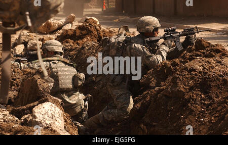 Stati Uniti Army Sgt. Auralie Suarez e Pvt. Brett Mansink prendere la copertura in un fossato al Doura, Iraq, 7 marzo 2007. I soldati sono da Charlie Company, 5° Battaglione, ventesimo Reggimento di Fanteria, 3° Brigata Team di combattimento, seconda divisione di fanteria e sono stati su un pattugliamento comune in Al Rashid quando la loro unità ricevuta di piccole armi da fuoco Al Doura. Il personale Sgt. Sean A. Foley Foto Stock