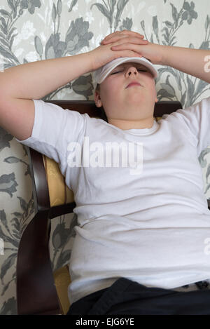 Adolescente ragazzo seduto su una sedia in salotto Foto Stock