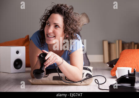 Ragazza guardando verso l'alto tenendo il ricevitore del telefono verso il basso come se la conversazione annoiato il suo Foto Stock