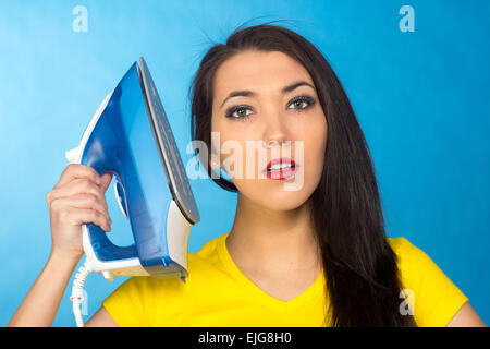 Houseworks, donna con il mucchio di vestiti per la stiratura, su sfondo blu Foto Stock