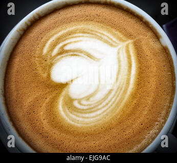 Primo piano della schiuma (crema) su un caffè cappuccino in una tazza di porcellana bianca Foto Stock