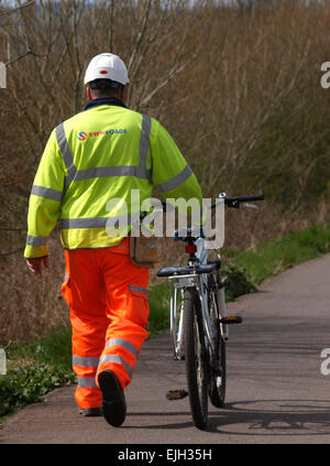 Lavoratore di strada camminando home spingendo bicicletta, Exeter, Devon, Regno Unito Foto Stock