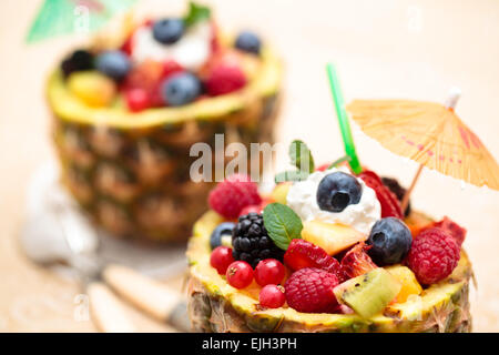 Insalata di frutta fresca nella tazza di ananas con kiwi, arancio, bacche e foglie di menta ( Focus sul pezzo di fragola). Foto Stock