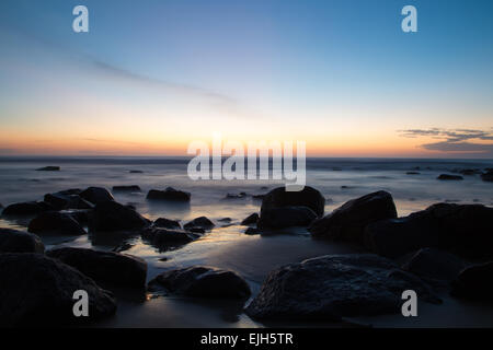 La rottura dell'alba in spiaggia e rocce sulla riva del mare Foto Stock