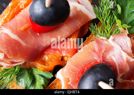 Crostino con prosciutto, verdi e pomodori. Le olive per la decorazione. Vista superiore Foto Stock