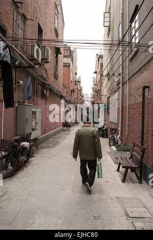 Residenti a piedi attraverso un antico quartiere residenziale nel centro cittadino di Shanghai, Cina Foto Stock