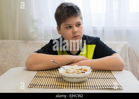 Ragazzo adolescente si rifiuta di mangiare i fiocchi d'avena per la prima colazione Foto Stock