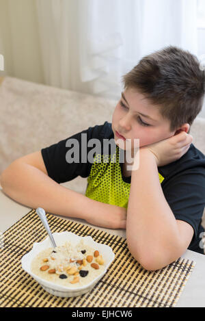 Ragazzo adolescente si rifiuta di mangiare i fiocchi d'avena per la prima colazione Foto Stock