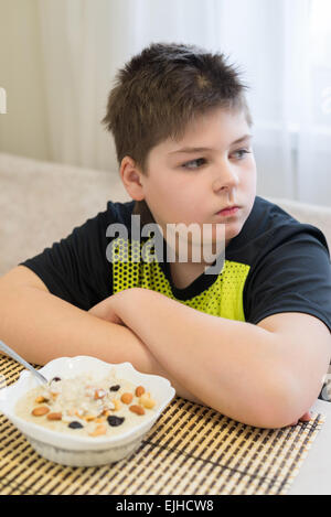 Ragazzo adolescente si rifiuta di mangiare i fiocchi d'avena per la prima colazione Foto Stock