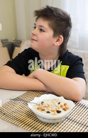 Ragazzo adolescente si rifiuta di mangiare i fiocchi d'avena per la prima colazione Foto Stock