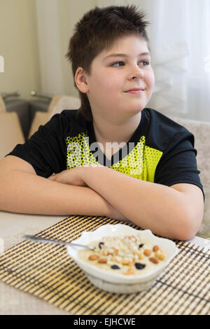 Ragazzo adolescente si rifiuta di mangiare i fiocchi d'avena per la prima colazione Foto Stock
