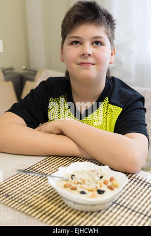 Ragazzo adolescente si rifiuta di mangiare i fiocchi d'avena per la prima colazione Foto Stock