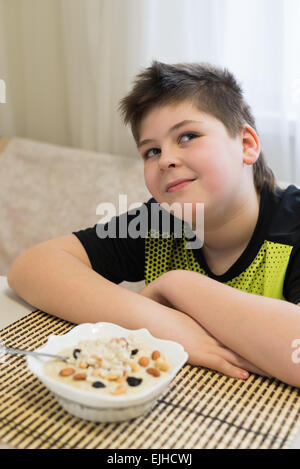 Ragazzo adolescente si rifiuta di mangiare i fiocchi d'avena per la prima colazione Foto Stock