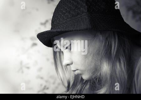 Monocromatico profilo closeup ritratto della bella bionda ragazza adolescente in black hat Foto Stock