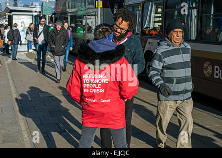 Un lavoratore di beneficenza, o chugger, lavorando per la Croce Rossa britannica affronta un pedone su Princes Street, Edimburgo, Scozia, Regno Unito. Foto Stock