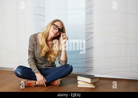 Ragazza la lettura di un libro seduti sul pavimento Foto Stock