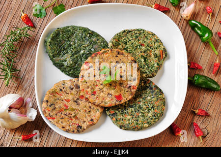 Alcune diverse materie veggie hamburger in una piastra su una tavola in legno rustico Foto Stock