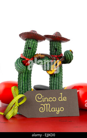 Happy Cinco de Mayo concetto con divertimento banda Mariachi giocatori di cactus e biglietto di auguri su rosso tavolo in legno. Foto Stock