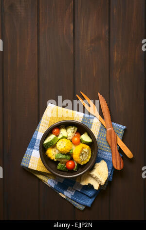Scatto dall'alto di una ciotola di verdure al forno di mais dolce, zucchine, pomodori ciliegia con timo Foto Stock