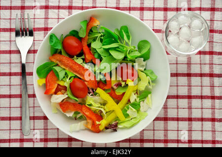 Insalata con vetro di acqua sulla tovaglia - elevato angolo di visione Foto Stock