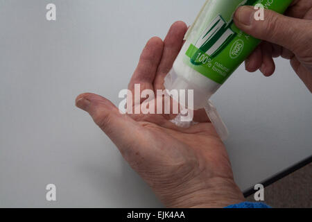 Donna anziana a mettere mano la crema su vecchie mani secche moisterising vecchia pelle secca Foto Stock