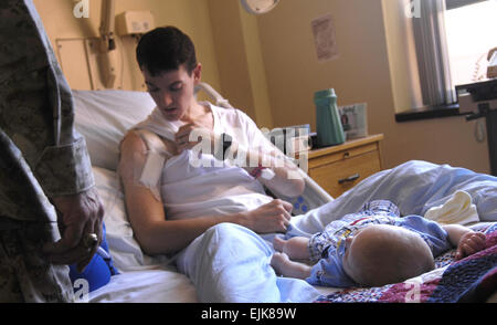 Stati Uniti Army Sgt. Johnson si siede sul suo letto di ospedale con il suo figlio di 3 mesi mentre mostra Presidente del Comune di capi di Stato Maggiore della Marina dello Staff gen. Pietro ritmo lesioni sostenne mentre di pattuglia in Iraq presso il Tripler Army Medical Center a Honolulu, Hawaii, Giugno 5, 2007. Il personale Sgt. D. Myles Cullen, U.S. Air Force. Foto Stock