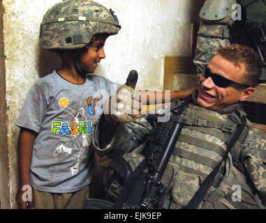 Stati Uniti Army Spc. Kirby Wasson, dal 3° Stormo, 2° Stryker reggimento di cavalleria, interagisce con un bambino iracheno dopo la ricerca in casa ott. 29, 2007 a Baghdad, Iraq. Spc. Luca Thornberry Foto Stock