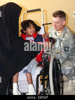 Army Sgt. Lonnie Todero, un medic con il primo squadrone, xxxiii cavalleria, 3° Brigata Team di combattimento, 101st Airborne Division Air Assault, effettua le regolazioni di Zeanib Saad Al Amary la carrozzella dic. 13, 2007 a Palazzo Radwaniyah complesse operazioni civile-militare centro in Iraq. Sgt. 1. Classe Kerensa Hardy, STATI UNITI D'AMERICA Foto Stock