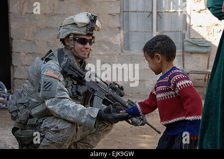 Un U.S. Soldato dell'esercito dalla società Delta, 1° Battaglione, trentesimo Reggimento di Fanteria, 2° Brigata Team di combattimento, terza divisione di fanteria saluta un ragazzo locale in Al Buaytha, Iraq, nov. 17, 2007. Spc. Angelica Golindano Foto Stock