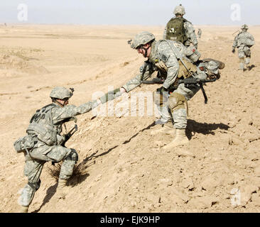 Stati Uniti Pfc dell'esercito. Ryan Mahan aiuta Spc. Stephen McLain fino alla cima di una collina in Chinchal, Iraq, 8 gennaio, 2008. I soldati sono assegnati al 3° plotone, Alfa truppa, 1° Stormo, 71st reggimento di cavalleria, 1° Brigata Team di combattimento, decimo Montagna divisione. Spc. Laura M. Buchta Foto Stock