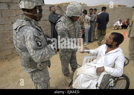 Stati Uniti I soldati dell esercito da Alfa batteria, 1° Battaglione, decimo campo artiglieria, terza divisione di fanteria mano out fornisce ai paesani durante un intervento di medicina a Sabah Nissan, Iraq, Marzo 27, 2008. Spc. Daniel Herrera Foto Stock