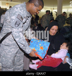 Sgt. Ramon Melocarela, un esercito di riserva di salute mentale uno specialista con la 113Med Co, combattere lo stress, dà una coperta per un iracheno donna e bambino al civile e militare del Centro operazioni, Camp vittoria, Iraq. Sgt. Melocarela, originariamente dalla Repubblica dominicana hanno recentemente raggiunto il suo U.S. La cittadinanza mentre in servizio in Iraq. Egli visita regolarmente il centro con oggetti donati che egli è stata raccolta per mesi dalla sua riends e vicini a Puerto Rico. Foto Stock