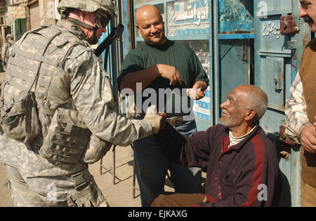 Stati Uniti Army Sgt. 1. Classe Marc Biletski, dal bravo Company, 1° Battaglione, XXIII Reggimento di Fanteria, seconda divisione di fanteria, saluta un iracheno civile con una stretta di mano durante un combinato di cordon e cerca con soldati dell'esercito iracheno in Rusafah, Iraq, 11 gennaio 2007. Sgt. Tierney Nowland Foto Stock
