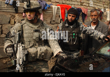 Stati Uniti Army Spc. Cory Jones, dal falco nero Company, 1° Battaglione, XXIII Reggimento di Fanteria, 3° Brigata Team di combattimento, seconda divisione di fanteria, e un iracheno poliziotto nazionali fornire protezione durante un combinato di cordon e ricerca nell'Shaab/Ur area di Baghdad, Iraq, Feb 17, 2007. Sgt. Tierney Nowland rilasciato Foto Stock