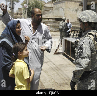 Un U.S. Soldato dell'esercito con il quarto plotone, Delta Company, 2° Battaglione, dodicesimo Reggimento di Fanteria, 2° Brigata Team di combattimento, seconda divisione di fanteria di Fort Carson, Colo., colloqui con i residenti locali circa la cui casa è stata colpita da armi da fuoco insorti nella zona della Dora nel sud di Baghdad, Iraq, 23 luglio, 2007. Master Sgt. Jonathan doti Foto Stock